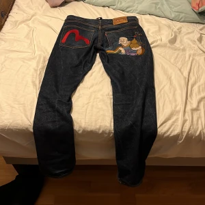 Evisu jeans - Evisu jeans med tryck på fickorna. Byxorna är i väldigt bra skick då det ända tecknet av användning är vid knappen.   Priset kan diskuteras vid snabb affär.