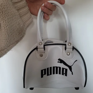 Puma väska - Jätte cool puma handväska i hyfsat bra skick. Den är i fejk läder. Den har ett kort handtag så man får hålla den i handen. Lite små missfärgningar men mest på ställen man inte kollar som undersidan. 