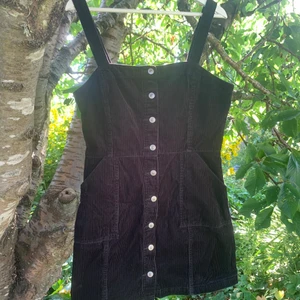 Manchesterklänning HM strl.42 - Svart manchesterklänning från HM Divided i storlek 42. Insydd i midjan och har fickor fram. Silvriga knappar som går att öppna hela vägen.