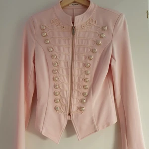 Rosa slim fit blazer/kavaj, storlek S 34/36 från Papillone - Fin sommarjacka med silver knappar, stängs med dragkedja. Fint öppen som stängt. Nyskick, 95% bomull, 5% elastan. Inte några skador, fläckar eller slitage. Rök- och djurfritt hem. Storlek 34/36 Längd: 50 cm Ärmlängd: 48 cm Tvättad med handtvätt i maskin. 