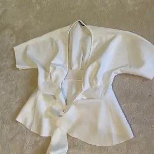 En vit tröja med ett bälte runt midjan och korta utsvängda armar, har aldrig användes. 