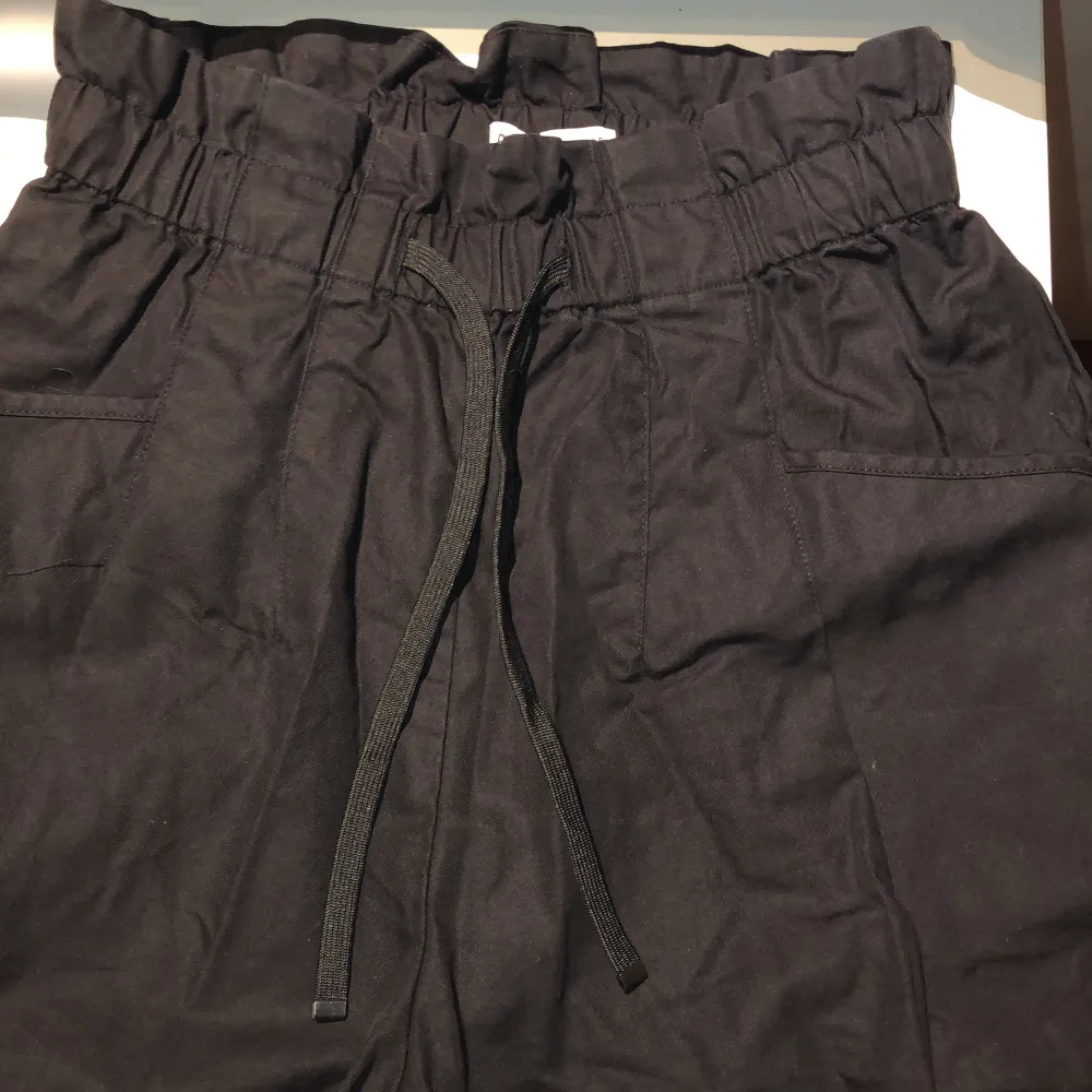 Loose-fitting paperbag Bermuda shorts with drawstring elastic waistband and pockets. Cotton blend. Mid to high waist depending on height. Metal hardware capping the drawstring. Gently used excellent condition. No holes, tears, rips, stains, snags, fading,. Shorts.