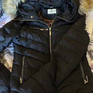 Damjacka, vinterjacka - Fin jacka som är använd 3 vintrar. Pälsens knappar/gummiband är lite i sönder men det går för den händiga att sy till. Har spruckit i armhålan på ett ställe i själva leopardmönstret. Går att sy.   Därav priset.