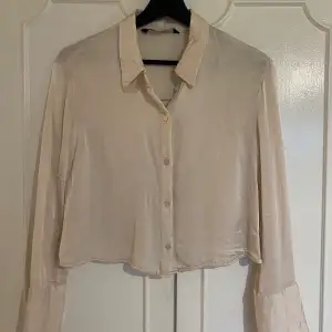 En crémevit, glansig, kroppad skjorta från Zara i storlek s.  Pris för frankt tillkommer