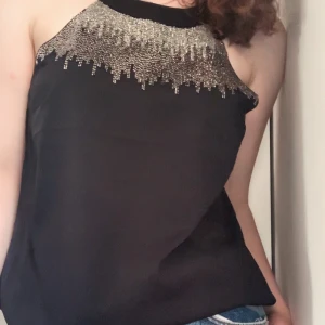 Topp med pärldetaljer - Ett linne från H&M med fastsydda ’pärlor’ på bröstet! Passar perfekt som festtopp då den både är bekväm och dekorerad! Jättefint skick, knappt använd och passar till det mesta. Skriv gärna om du har frågor!