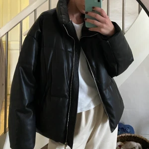 Fauxlether dunjacka  - Dunjacka i konstläder från Ginatricot. Väldigt fint skick, i princip som ny! Jag har XS/S vanligtvis & är 174 lång (köpte större för att få en oversize look) Säljes pga kommer inte till användning! Nypris 799kr