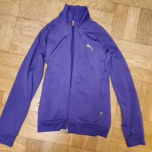 Puma träningströja - Lila långärmad träningströja från Puma. Silverringar i dragkedjor, 2 fickor. Använd enstaka gång, mycket fint skick. Okej att komma med bud. Katt i hemmet. 