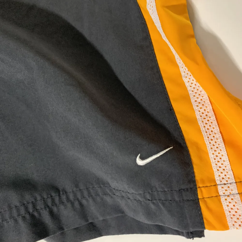 Nike trainings byxor från 90tals. Grå och orange med vits mesh. ”Mini swoosh” längst ner på ben. . Jeans & Byxor.