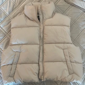 Beige väst - Säljer denna beiga puffväst från bikbok, använd Max två gånger så bra skick. Storlek m. Köparen står för frakten💕