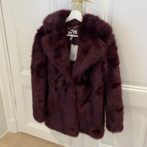 Vacker fuskpäls i vinröd färg JAKKE - Fuskpäls i vacker vinröd färg från JAKKE.  Storlek XS.   Jackan är helt oanvänd med prislapp kvar. Inköpt för nypris 2.300 sek.