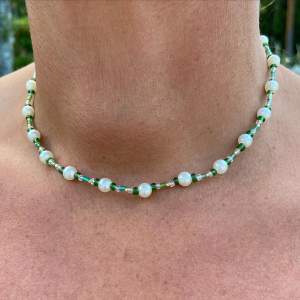 Ett grönt fint halsband med vita pärlor✨Elastiskt utan spänne och är handgjort!💕Frakt 15 kr