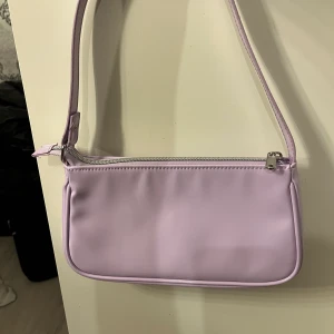 Lila väska  - Denna lila väskan är från HM och har silver detaljer. Säljer denna 55kr!
