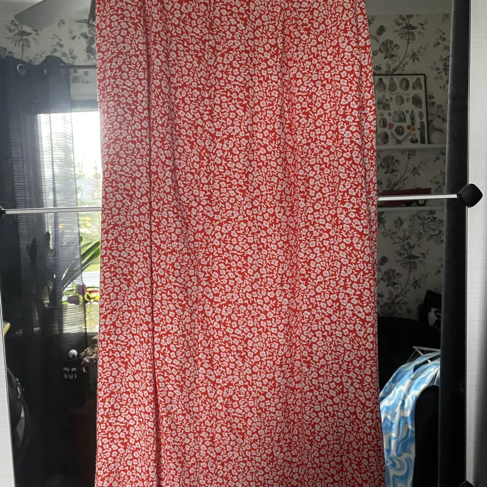 Lång röd kjol med blommor och en slits från HM. Storlek 36. 70kr plus frakt.. Kjolar.