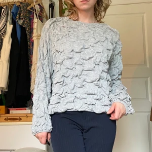 Grå Carin Wester långärmad tröja - Grå långärmad tröja från Carin Wester med ”bubblor” mönster. Är stor i storleken så passar lätt M. Ganska så tung och varm vilket passar till hösten.  Du som köper står för frakt, möts annars upp vid Stockholm city.