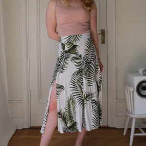 Kjol, storlek 38 - Söt kjol med palmblad från H&M i storlek 38. Med slits. Modellen på bilden är 160 cm. 