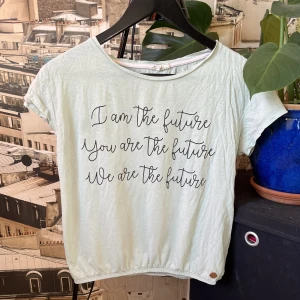 T-shirt  - Ljusgrön T-shirt från KappAhl med text på. Använd men inga täcken på slitage. Skulle säga att den är aningens croppad efter som det finns ett typ av elastisk band.