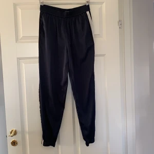 Byxor - Satin aktiga joggers/byxor blåa med vita revärer på sidorna. Retro stuk men fickor 