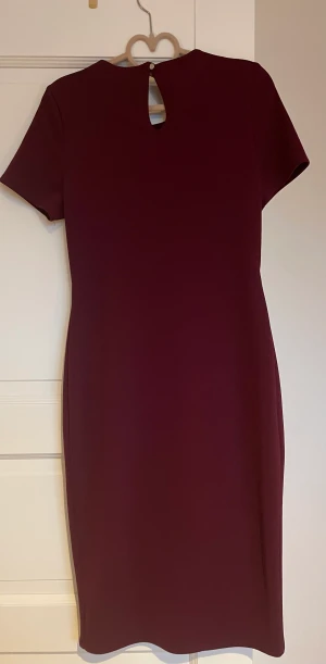 Vinröd klänning - Använd 1 gång, för liten nu. Längd totalt 105 cm. Fin, figursydd klänning i kraftigare bomullstyg. Nyskick