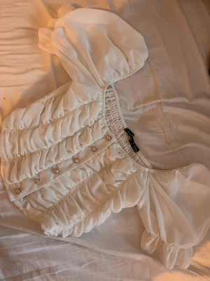 Vit topp med knappar - Vit topp med knappar och puffärmar. Storlek S från Boohoo. Använd en gång.