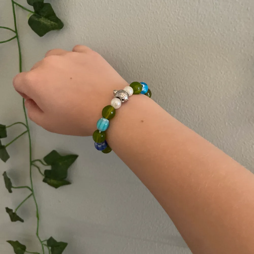 Armband med glaspärlor i grön, vit och blå och en silvrig sköldpadda. ❤️🐢. Accessoarer.