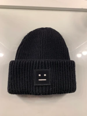 Acne mössa - Säljer min svarta mössa från Acne då jag inte använder den. Har inte använt den mycket och den har inga fläckar eller skador. Varm och snygg, perfekt nu till vintern. Pris kan diskuteras