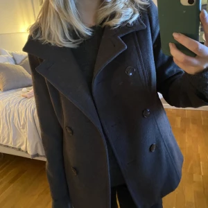 Kort kappa - Trendig. Köpt för längesen från H&M! Mörkgrå, lite urtvättad svart i färgen. Storlek 40 men sitter som en 34-36 på mig som är 165cm