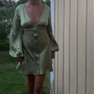 Grön satin klänning - Helt ny klänning i storlek 34, glömde lämna tillbaka då jag valde en annan klänning. Öppen i ryggen. 600kr nypris. 