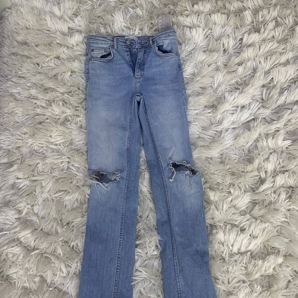 Ett par högmidjade jeans från Zara. Har inte använt dem så ofta så de finns inga skador eller liknande på byxorna. De finns två hål vid knänen som jag inte har klippt utan köptes så. . Jeans & Byxor.
