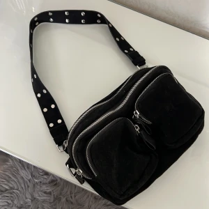 Svart väska  - Säljer denna svarta noella inspirerade väskan, knappt använd. Man får plats med mycket i den och det finns ett längre band till den som man får med. Säljer då jag inte får användning för den