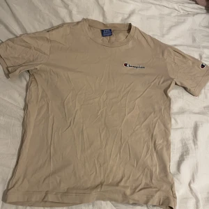 Champion T-Shirt - Används inte längre då den är för liten. Rätt så stilren tröja annars och funkar till det mesta. Har ett ytterst litet hål precis vid loggan men annars felfri. Storlek M men får nog plats som S