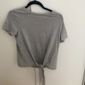 Grå t-shirt med knytning  - Knuten går att fixa som man vill. Fint material i stretch. Storlek M.
