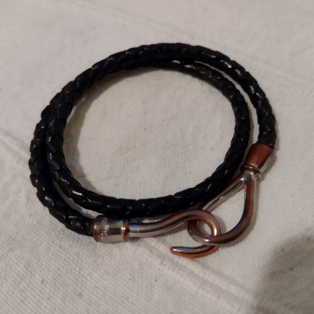 Svart flätat armband i läder, från Mint. Silver- och kopparfärgat lås. Har varit helt silverfärgat men blivit mer kopparfärgat med tiden. Läderbandet är inte slitet. . Accessoarer.