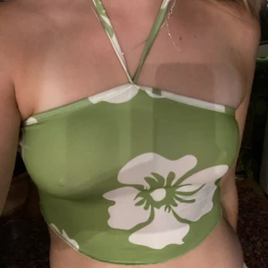 Grönt linne - Supersött grönt linne med små vita blommor. Man knyter runt halsen med banden och tröjan är i ett stretchigt material. Köpt tröjan på shein  och den är i storlek S. Fraktar eller möts i sthlm. Pris ej inkl frakt💞