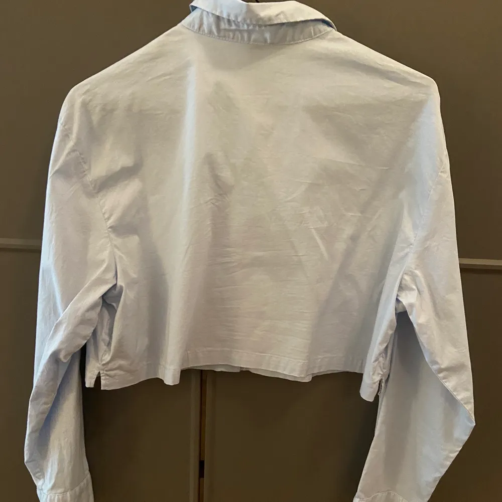 Ljusblå croppad skjorta från H&M.  Använd fåtal gånger.  Storlek S men passar bäst en 34.  Ord pris 99kr. Skjortor.