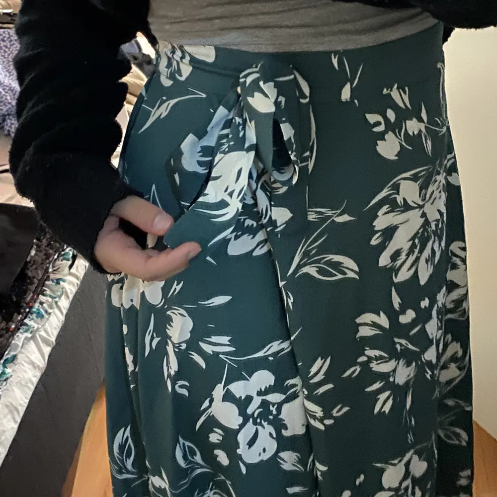 En grön lång blommig kjol från Shein i storlek 38. Omlott och ger därför en slits på ena benet. Super skön och band i midjan för att knyta hårdare/lösare.. Kjolar.