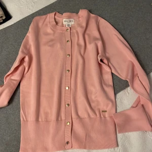 Holly& White finstickad cardigan by Lindex - Cardigan med lång ärm och små guldfärgade knappar framtill. MATERIAL: 77% viscose 23% polyester. Materialet kommer från ansvarsfullt odlad skog. Fintskick, secondhand använd fåtal ggr. EU small.