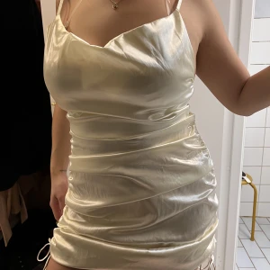 Champagne kläning - Tajt champagne kläning med snören på sidorna. Änvänd två gånger 