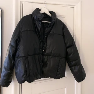 Vero Moda svart pufferjacka i skinnimitation - Snygg oanvänd jacka med prislappar kvar. Inköpt på Vero Moda för 649kr. Jackan är i en kort, vadderad modell med ett yttertyg i skinnimitation. Jackan stängs med tryckknappar. Skriv för fler bilder. Storleken är Medium men passar även small. 
