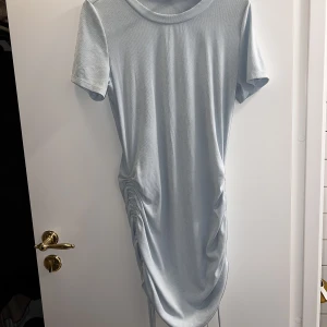 Kläning - Säljer en ljus blå kläning som man kan spänna på sidorna 