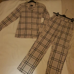 Pyjamas set  - Helt ny pyjamas set, skjorta med tillhörande byxor.  Skjortan har knappar samt en bröst ficka. Storlek xs/s