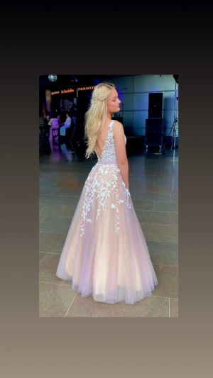 Rosa / mauve balklänning med blommiga detaljer - En jättefin balklänning jag hade förra året som nu ska få dansa vidare! Bara använd en gång. Jag är 164cm lång och hade ca 10 cm höga klackar på mig. Är i storlek S/XS, och går både att sy in och klippa på längden ifall det behövs. Köptes för 5 500kr. 