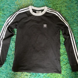 Svart långärmad Adidaströja  - Adidaströja i lite tjockare material och med muddar längst ner på ärmarna. Bra skick!