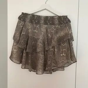 Jätte fin kjol med volang och grått ormskinnsmönster från Gina Tricot!  Använd fåtal gånger och är fortfarande i fint skick!  Den är stretchig i midjan och kan därför passa både storlek 34 eller 38! ⭐️