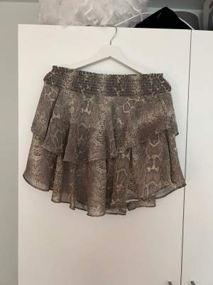 Jätte fin kjol med volang och grått ormskinnsmönster från Gina Tricot!  Använd fåtal gånger och är fortfarande i fint skick!  Den är stretchig i midjan och kan därför passa både storlek 34 eller 38! ⭐️