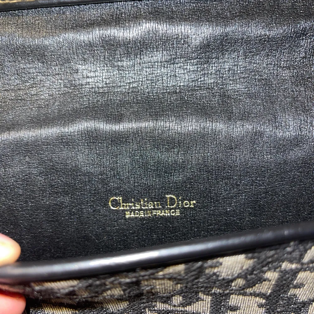 Äkta Dior handväska  Monogramcanvas med detaljer av skinn och guldfärgad metall. Märkt Christian dior, made in France. 1970/80-tal. Höjd ca 16 cm, bredd 21,5 cm.  Den är i bra skick. Den kan justeras så att bandet blir kortare/längre. . Väskor.
