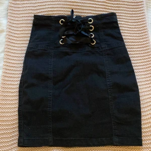 Jeanskjol med snygga detaljer - En jeanskjol som är från New Yorker. Den har som trådar där fram som är snyggt korsade med jeanstyg bakom så man inte ser igenom. Den är super snygg och får tyvärr sälja den då den inte passar längre. Knappt använd. Storlek 34. Pris kan diskuteras!