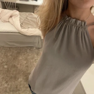 Festtopp H&M - Jättesöt halterneck-topp ifrån H&M i grått som passar superbra till middag/fest. Justerbar nacke, man kan alltså välja hur ”smal elelr bred” den ska vara. Har klippt av lappen så kommer ej ihåg storlek men passar 36-40 typ