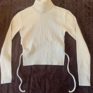 Långärmad topp - Jättefin beige tröja med en öppen rygg som man knyter. Den är köpt i turkiet men använde den aldrig för att jag glömde att jag hade den. Det står att den är S men skulle säga att den är mer åt XS efter som att kragen på tröjan är lite taight