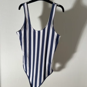 Randig body - Blå-vit randig body från bikbok. Använd 2-3 gånger så nyskick! Skönt material. Lite djup i ryggen☺️ den knäpps nertill med knappar. Storlek xs på lappen men passar även s