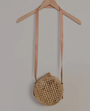 Retro väska - DETALJER  En snygg stråväska ger din look den rätta sommarkänslan. Denna runda variant med axelrem är dessutom en av chefsdesignerns personliga favoriter. Väskan är i flätad pappersstrå med en smal axelrem i brunt läder.